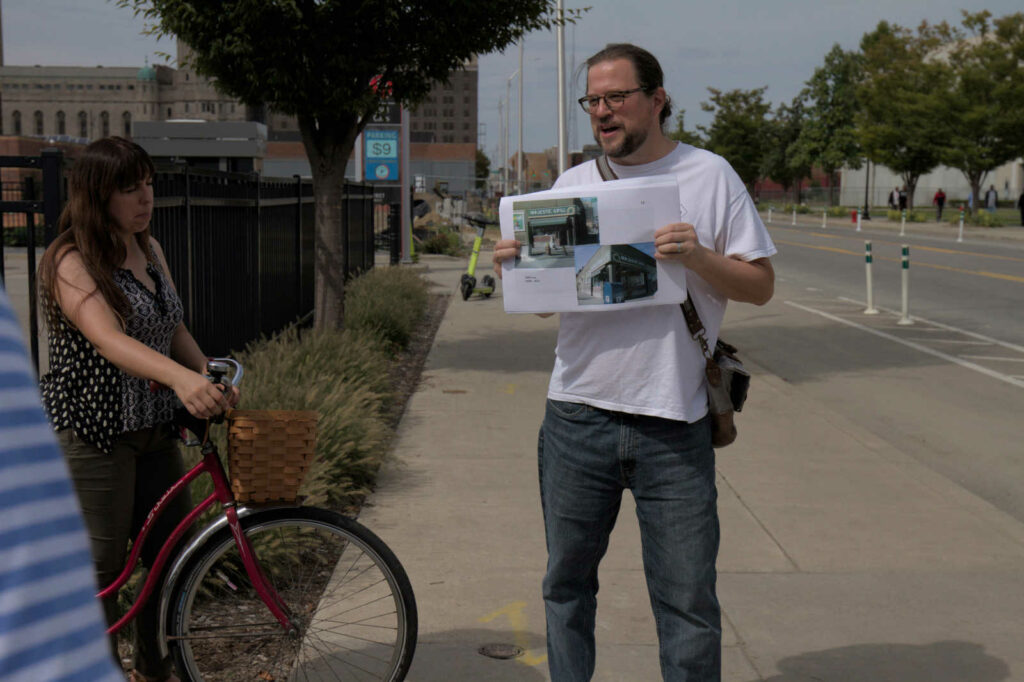 Francis Grunow of Detroiters for Parking Reform shows a historic photograph of the former Majestic Cafe at the corner of Cass and Henry, demolished around 2016 for a surface parking lot.